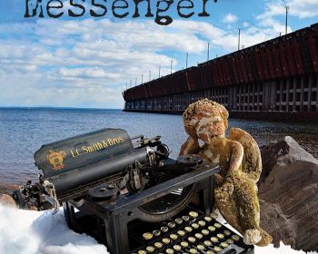 A vintage typewriter and a worn teddy bear positioned in a snowy landscape with a lake and wooden dock structure in the background, under a partly cloudy sky.