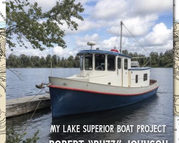 A small blue and white boat named Kathy Ann is docked on a lake under a partly cloudy sky. Trees line the shore in the background. Text on the image reads: "Building Kathy Ann, My Lake Superior Boat Project, Robert 'Buzz' Johnson.