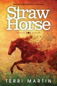 Book cover for "Straw Horse" by Terri Martin, featuring a silhouette of a running horse against a textured background with a large sun and earthy tones. The subtitle indicates it is the second Kat Wilde U.P. Mysteries book.