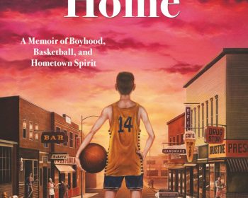 A boy wearing a yellow basketball jersey with the number 14 stands on a small town street at sunset, holding a basketball. The street is lined with shops, including a bar, bakery, hardware store, and drugstore.