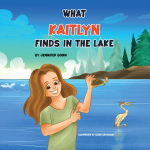 A smiling girl holds up a turtle by a lake, with a heron standing nearby and trees and blue sky in the background. The book title "What Kaitlyn Finds in the Lake" and author’s name appear at the top.